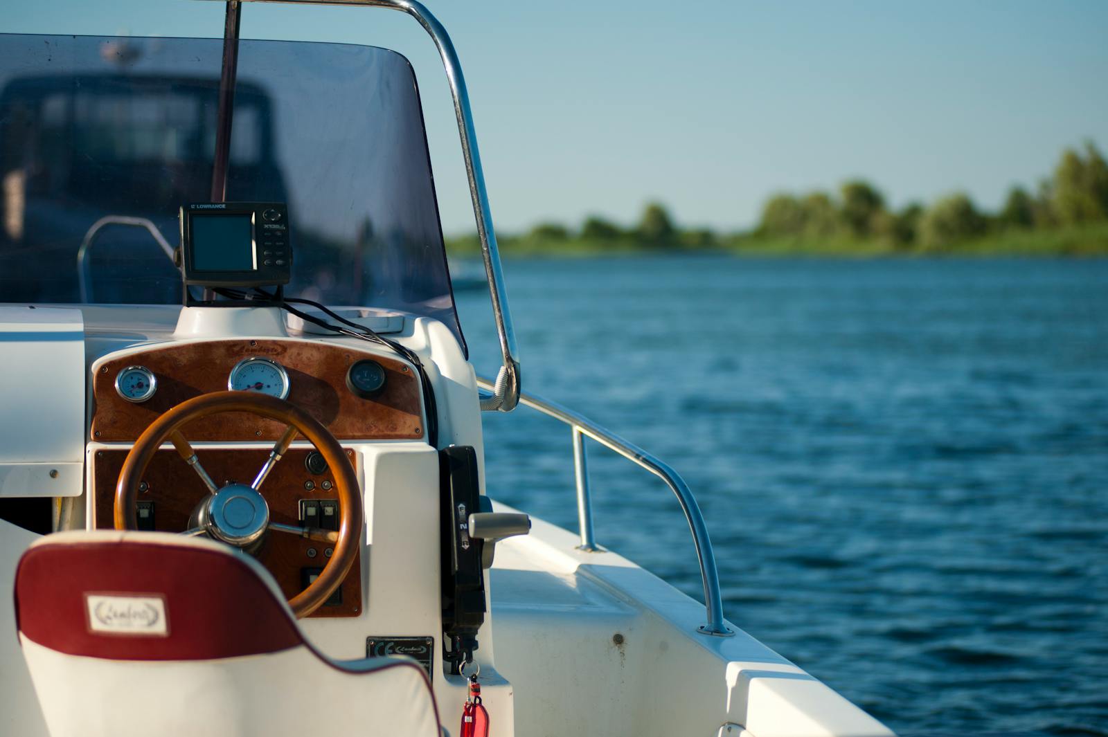 A yacht steering wheel with a serene water view during a bright summer day offering leisure and adventure.